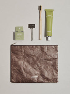 Elevated oral care essentials and metal toothpaste dispenser, housed in a water-resistant makeup pouch.